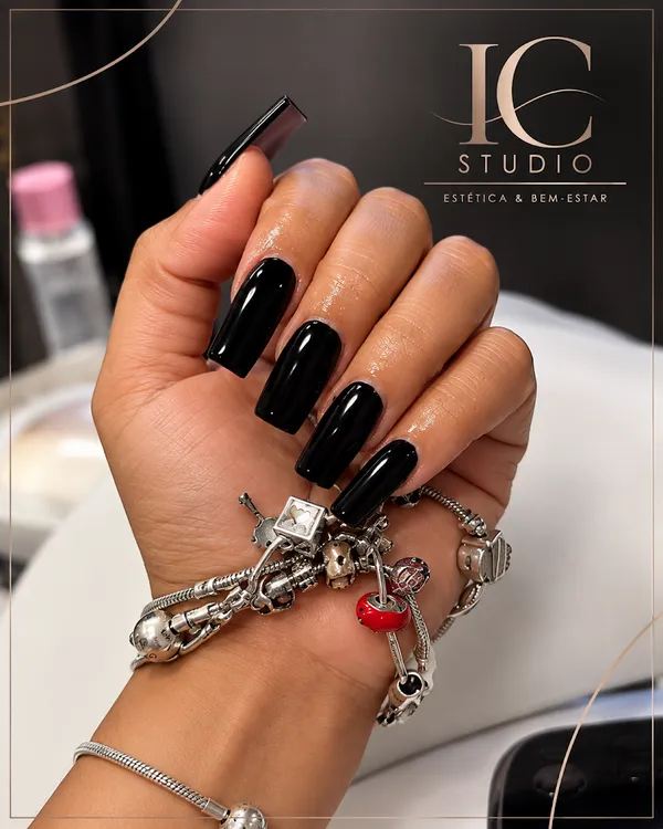 Mão com unhas de gel compridas em preto brilhante, com acabamento quadrado, feitas no IC Studio
