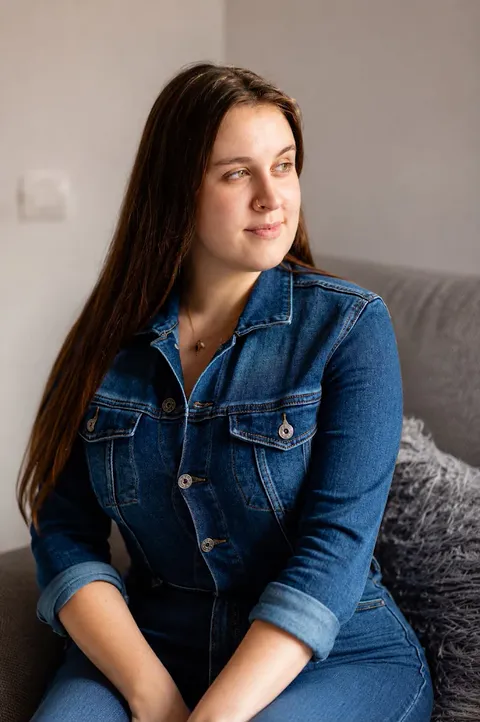 Retrato da responsável pelo IC Studio, sentada num sofá, com sorriso sereno e luz natural